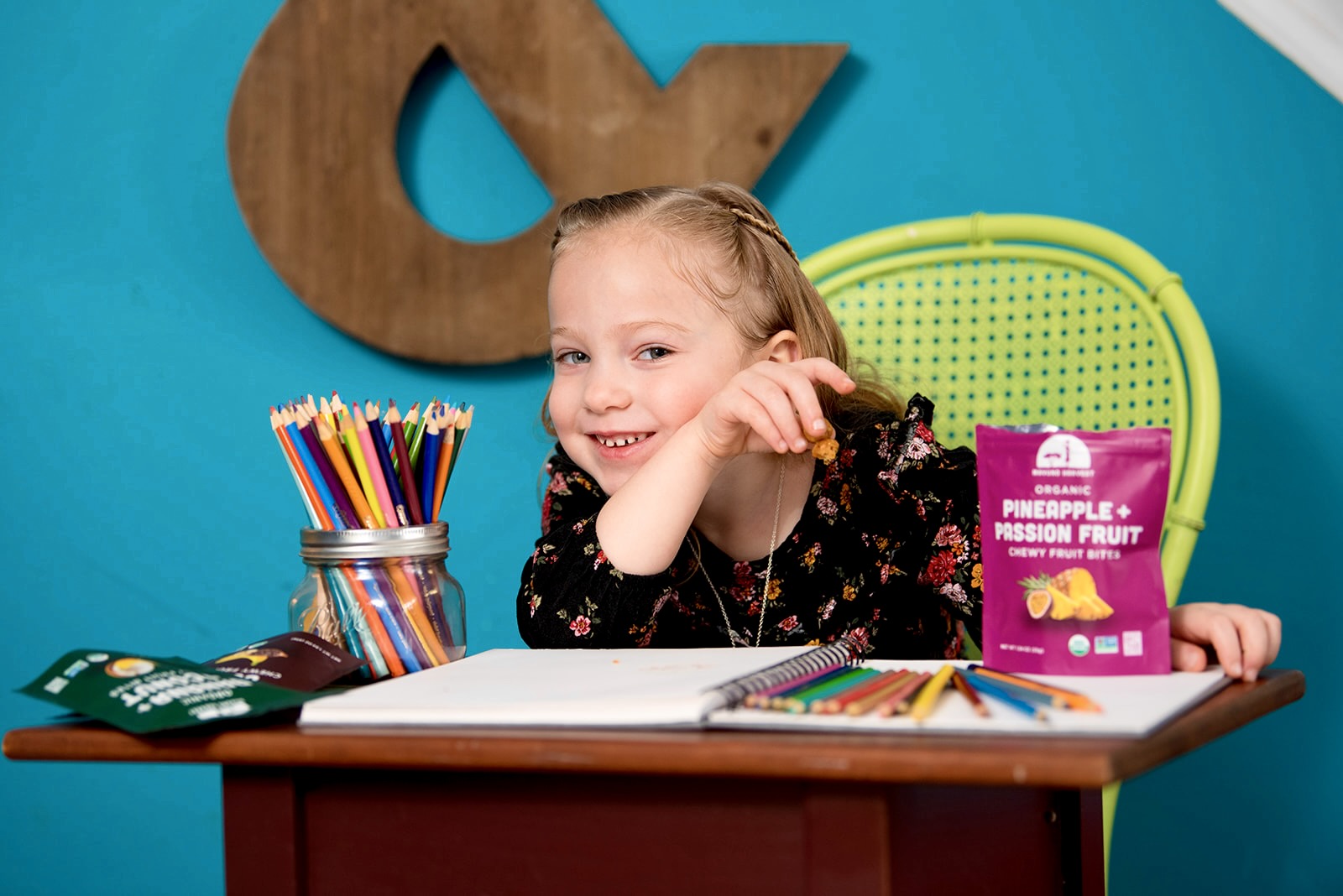 A child snacking on Pineapple and Passion Fruit Fruit Bites at a drawing table